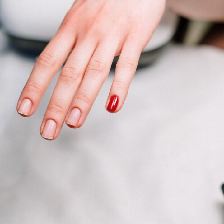 A person with red nail polish on their finger.