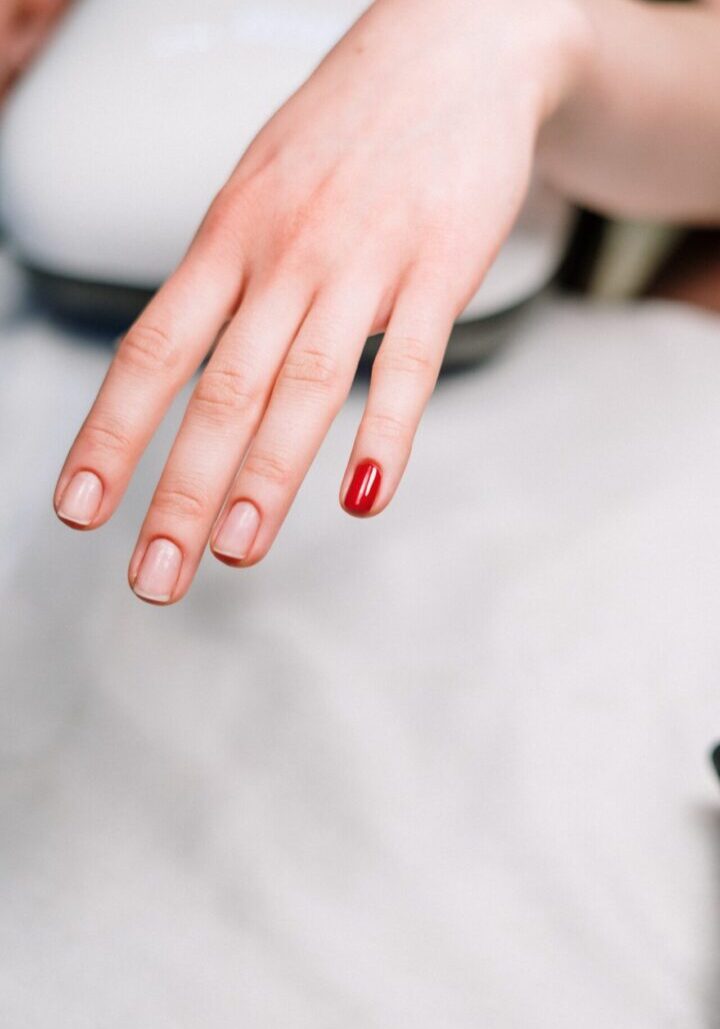 A person with red nail polish on their finger.